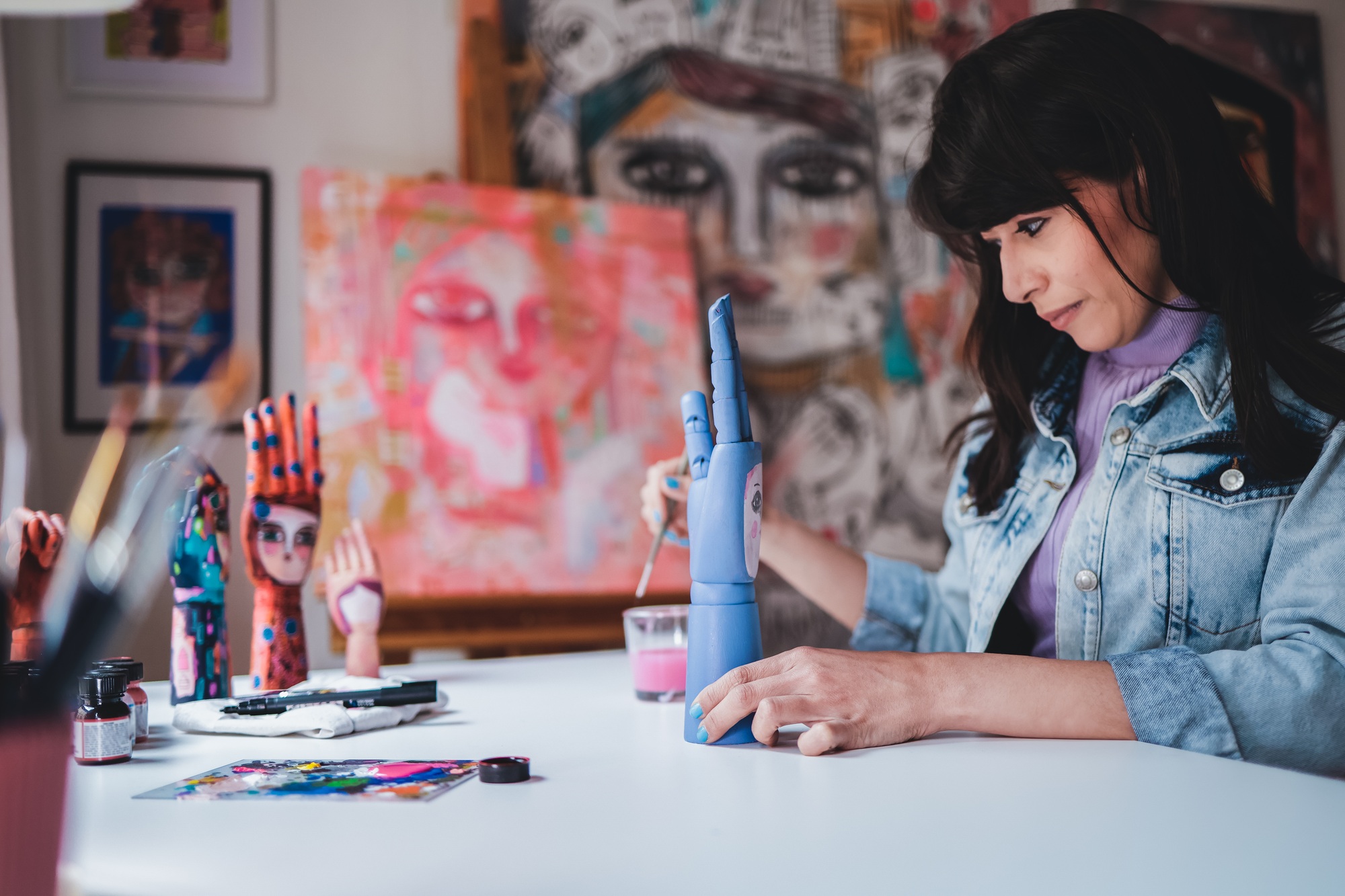 Young artist painting wood art piece inside art home studio atelier - Focus on right hand